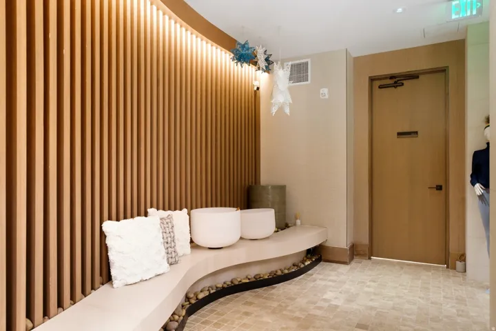 Curved built-in bench seating with a stone-filled base, complemented by a vertical wood-slat accent wall with integrated cove lighting