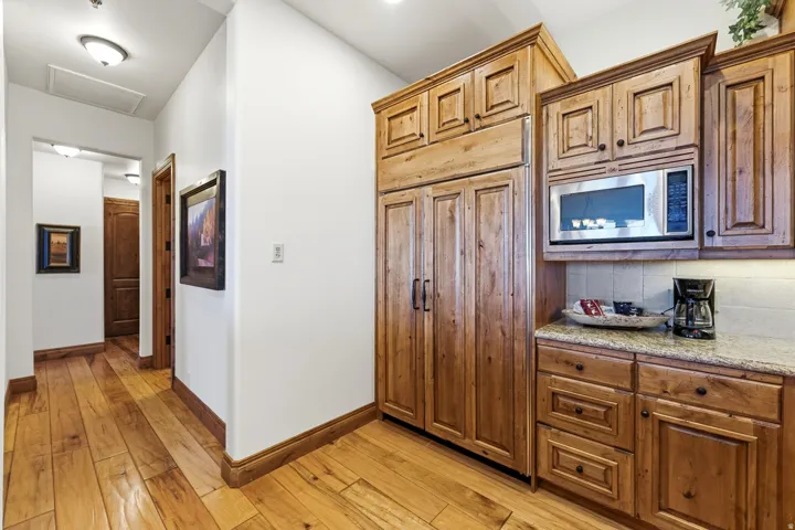 Kitchenette with wood-finish cabinetry, granite-style countertop, and stainless steel microwave