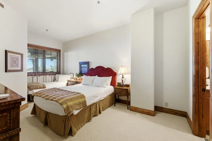 Carpeted room featuring a large window with wood trim, white walls, and wood baseboards