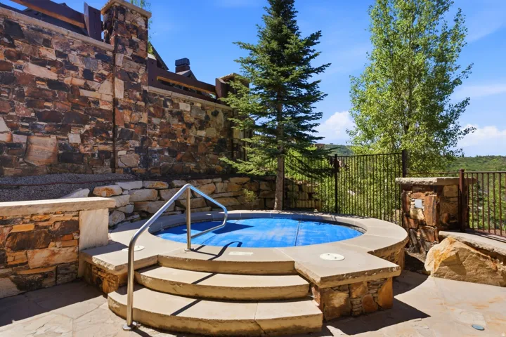 Circular spa with integrated stone steps and handrail, surrounded by a flagstone patio