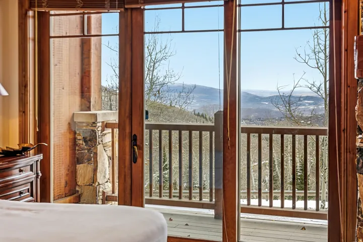 Sliding glass doors opening to a private balcony with a wooden railing and a stone pillar