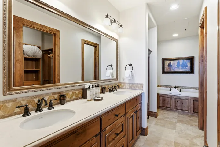 Dual vanity with wood cabinetry, light-toned countertop, and bronze fixtures