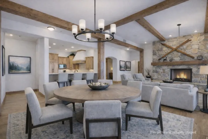Dining area featuring a circular wood-finish table and upholstered chairs, under a contemporary chandelier