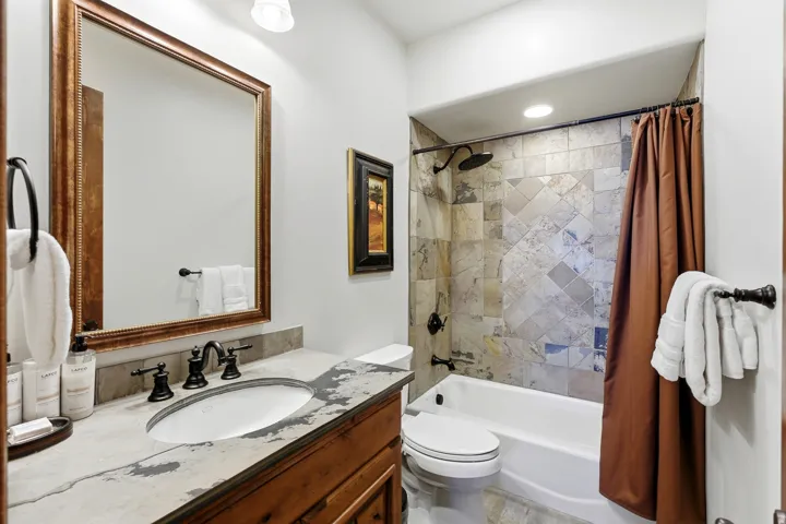 Bathroom featuring a built-in vanity with an undermount sink and dark bronze fixtures, a framed mirror, and recessed lighting