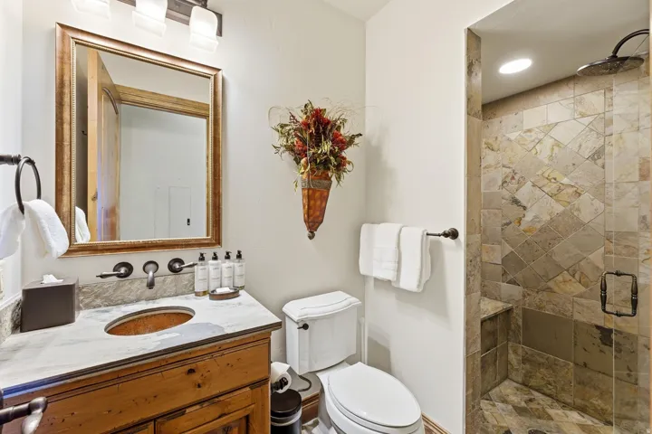 Bathroom featuring a wood vanity with a white stone countertop and undermount sink, a framed mirror, and a wall-mounted faucet