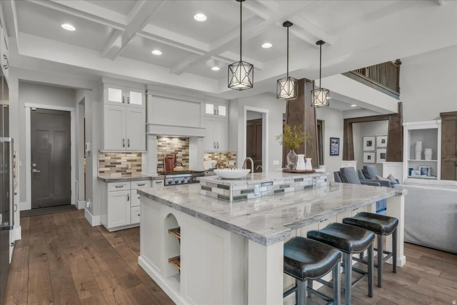 Kitchen featuring white cabinets, a kitchen breakfast bar, light stone counters, open floor plan, and coffered ceiling