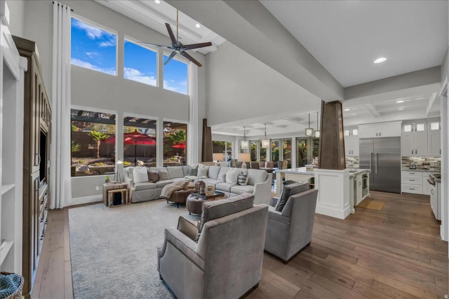 Living area with dark wood-type flooring, plenty of natural light, ceiling fan, a towering ceiling, and recessed lighting