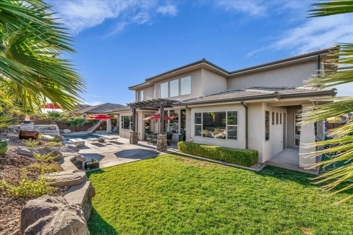 Back of house with a pergola, a patio area, stucco siding, a lawn, and a tile roof