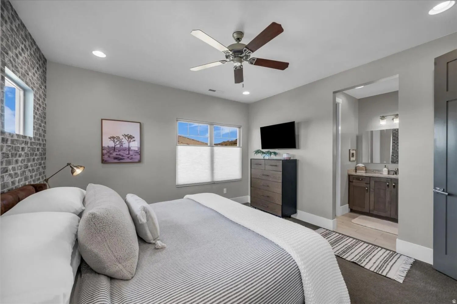 Bedroom featuring a ceiling fan, brick wall, connected bathroom, recessed lighting, and light carpet