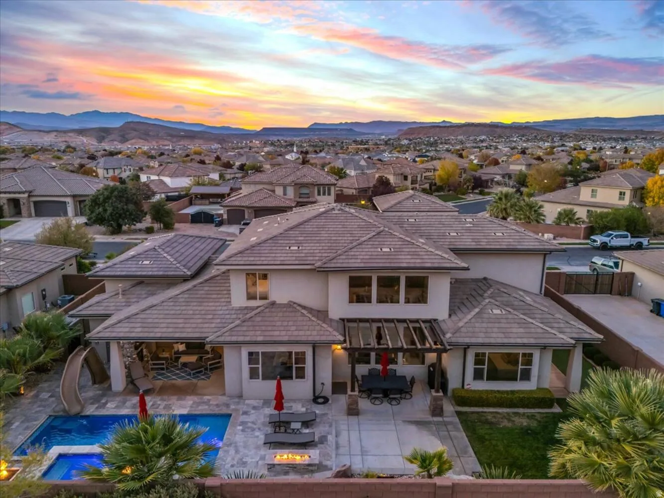 Back of property at dusk featuring a residential view, stucco siding, outdoor dining space, and a patio