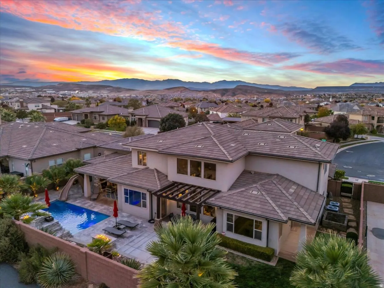 Back of house at dusk with stucco siding, a fenced backyard, a residential view, and a patio area