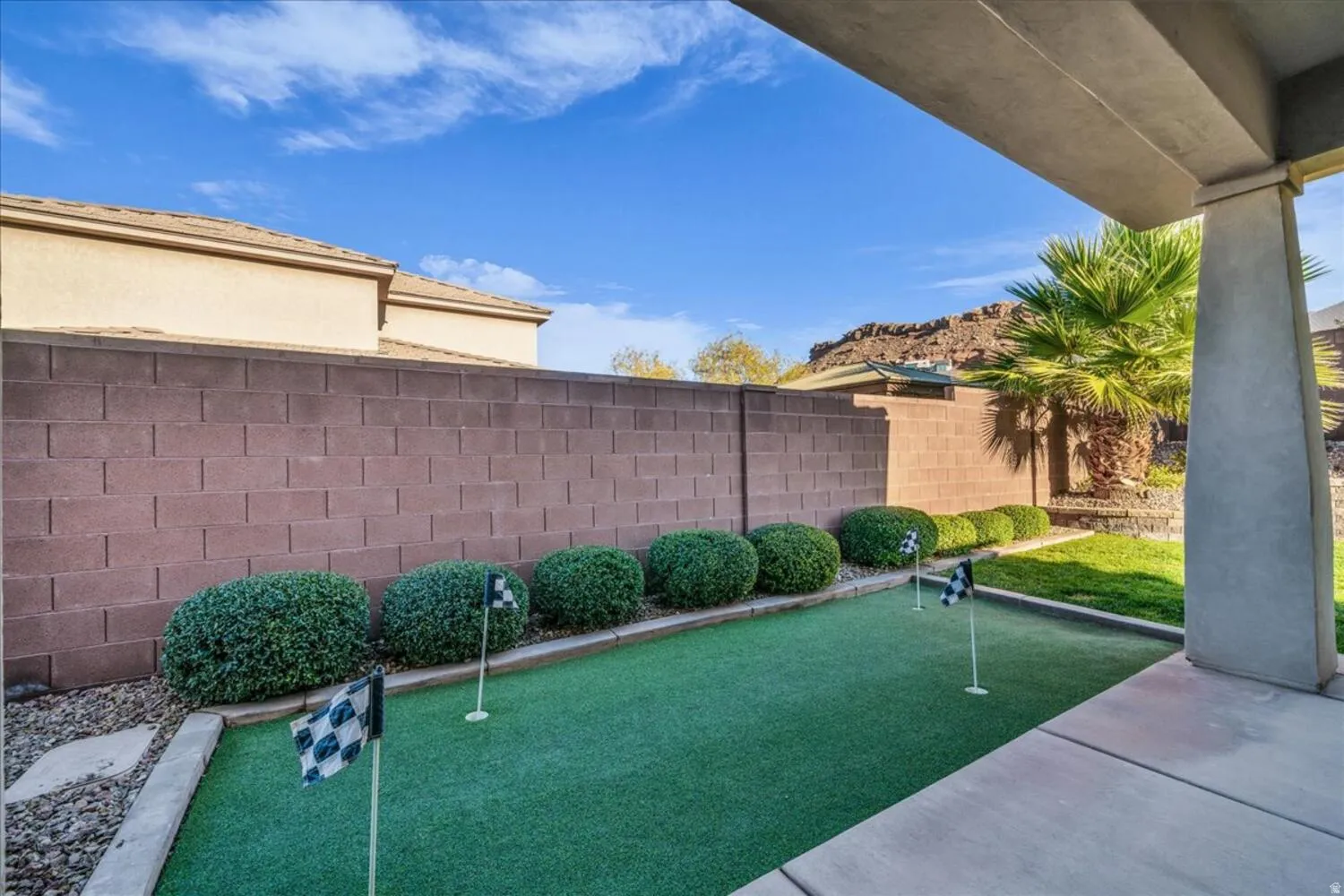 View of home's community with a putting area, a fenced backyard, and a patio