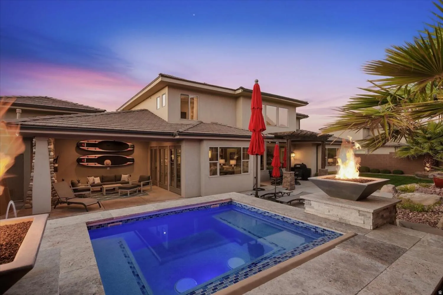 Back of property at dusk featuring a patio, an outdoor living space with a fire pit, stucco siding, a hot tub, and a tiled roof