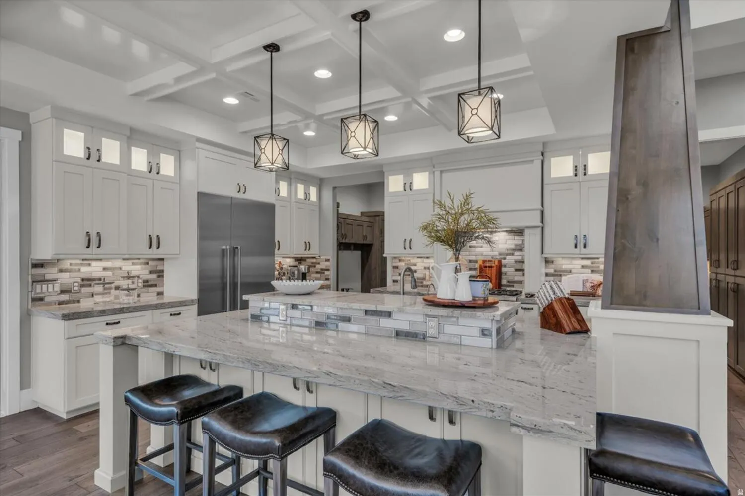 Kitchen featuring backsplash, a kitchen breakfast bar, glass insert cabinets, white cabinetry, and coffered ceiling