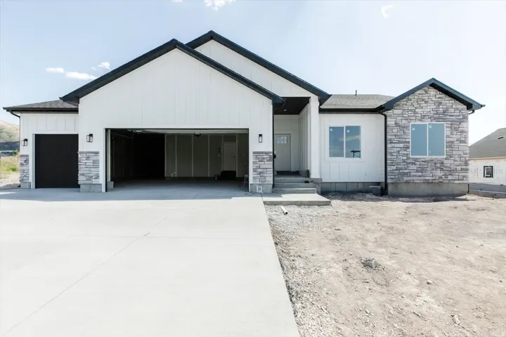 Modern farmhouse with board and batten siding, stone siding, and a garage