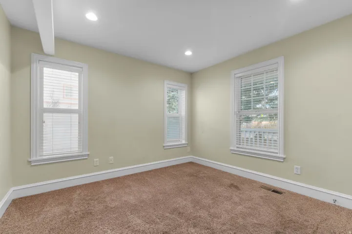 Empty room with healthy amount of natural light, carpet flooring, and recessed lighting