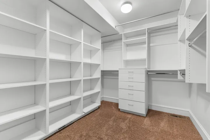 Walk in closet featuring dark colored carpet