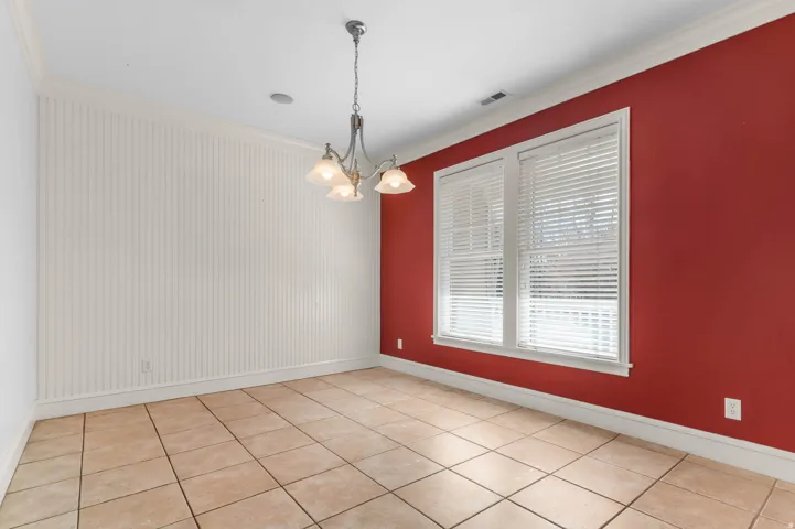 Empty room with ornamental molding, light tile patterned flooring, and a chandelier