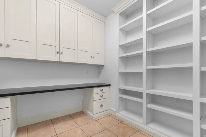 Unfurnished office featuring light tile patterned flooring and built in desk