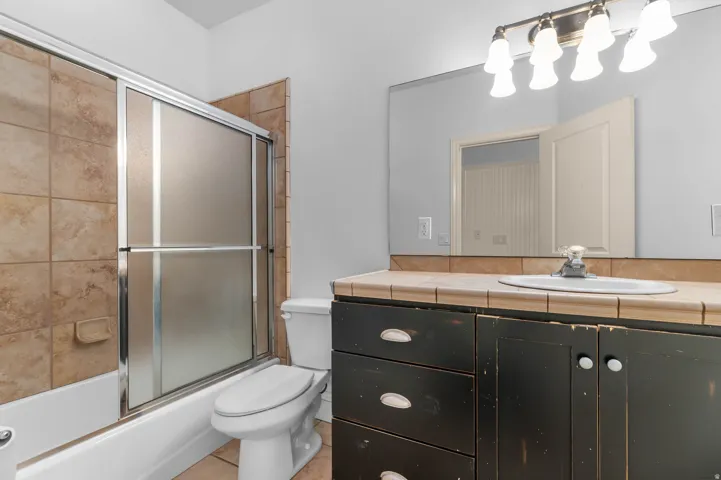 Bathroom with vanity, combined bath / shower with glass door, and light tile patterned flooring