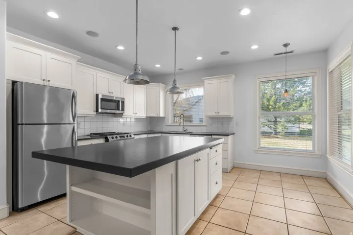 Kitchen with open shelves, backsplash, appliances with stainless steel finishes, light tile patterned flooring, and dark countertops