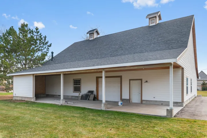 Back of house with a shingled roof and a yard