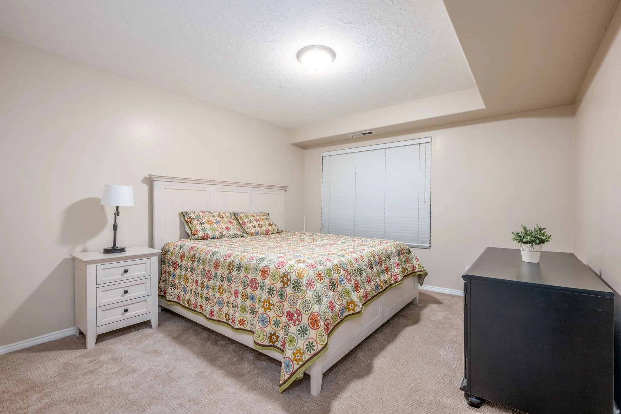 Bedroom featuring light carpet and a textured ceiling