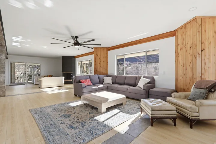 Living area featuring ceiling fan, wood walls, light wood-style floors, and ornamental molding