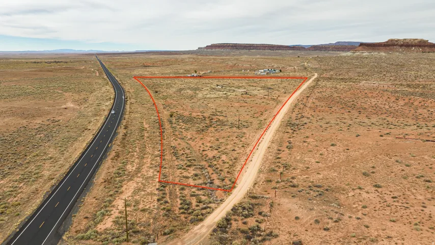 Aerial view of sparsely populated area with property parcel outlined and a mountainous background
