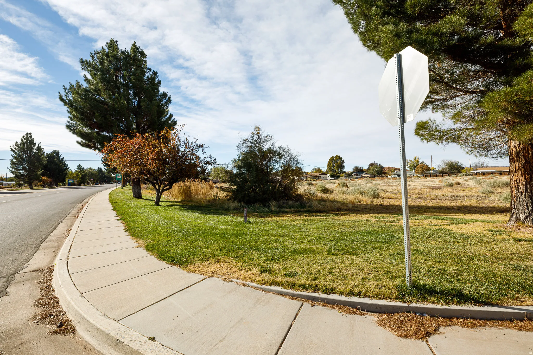 View of asphalt street featuring curbs, traffic signs, and sidewalks