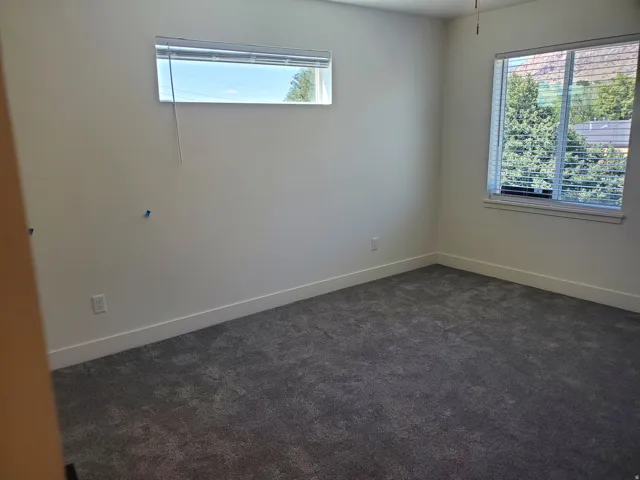 Empty room with dark colored carpet and baseboards