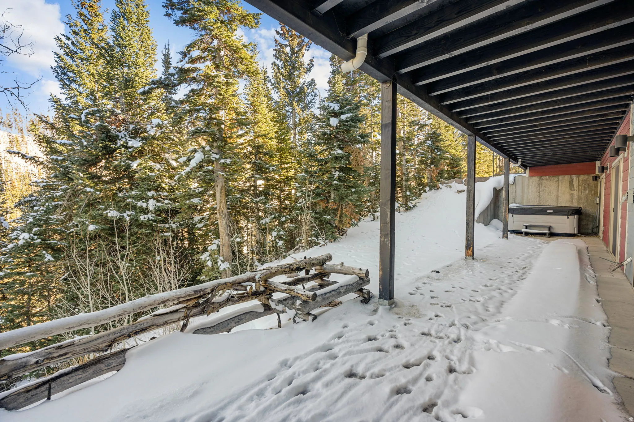 Snow covered patio featuring a hot tub