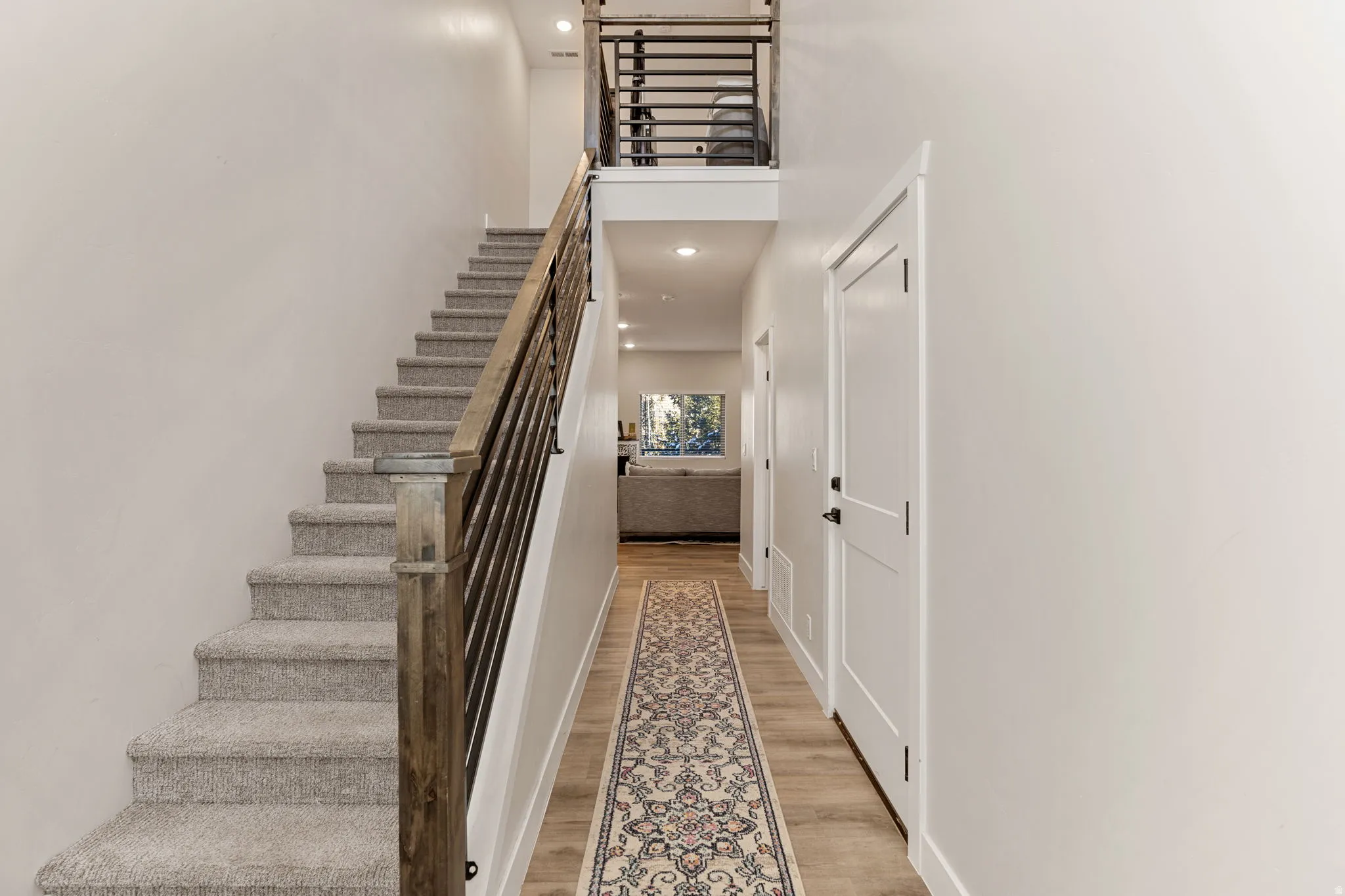 Staircase featuring a high ceiling, wood finished floors, and recessed lighting