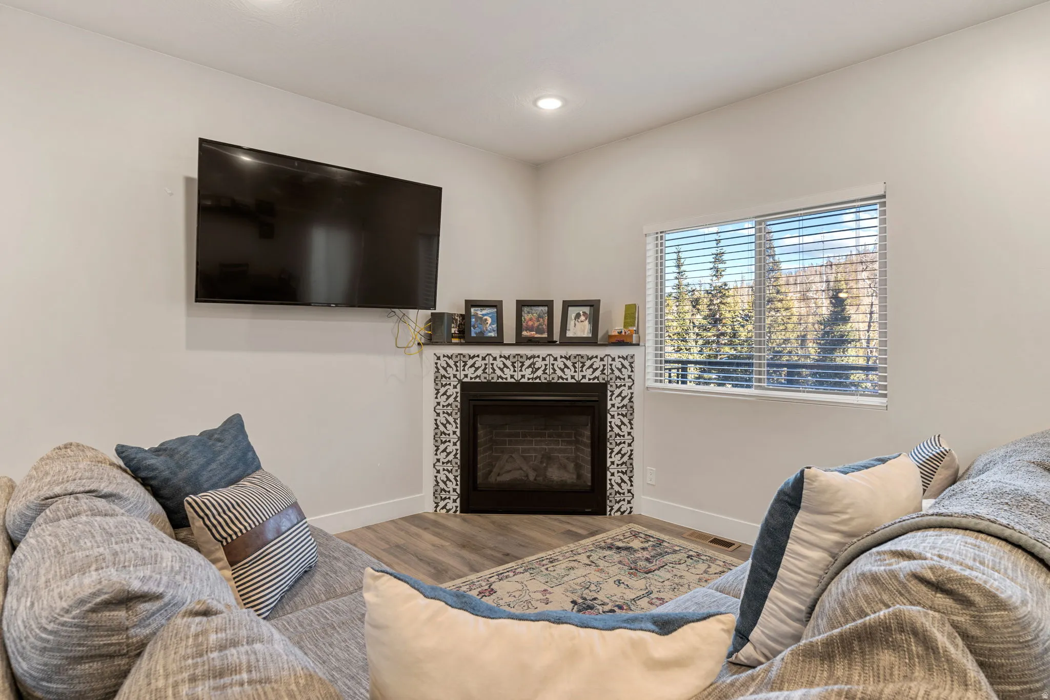 Living room with wood finished floors, a fireplace, and recessed lighting