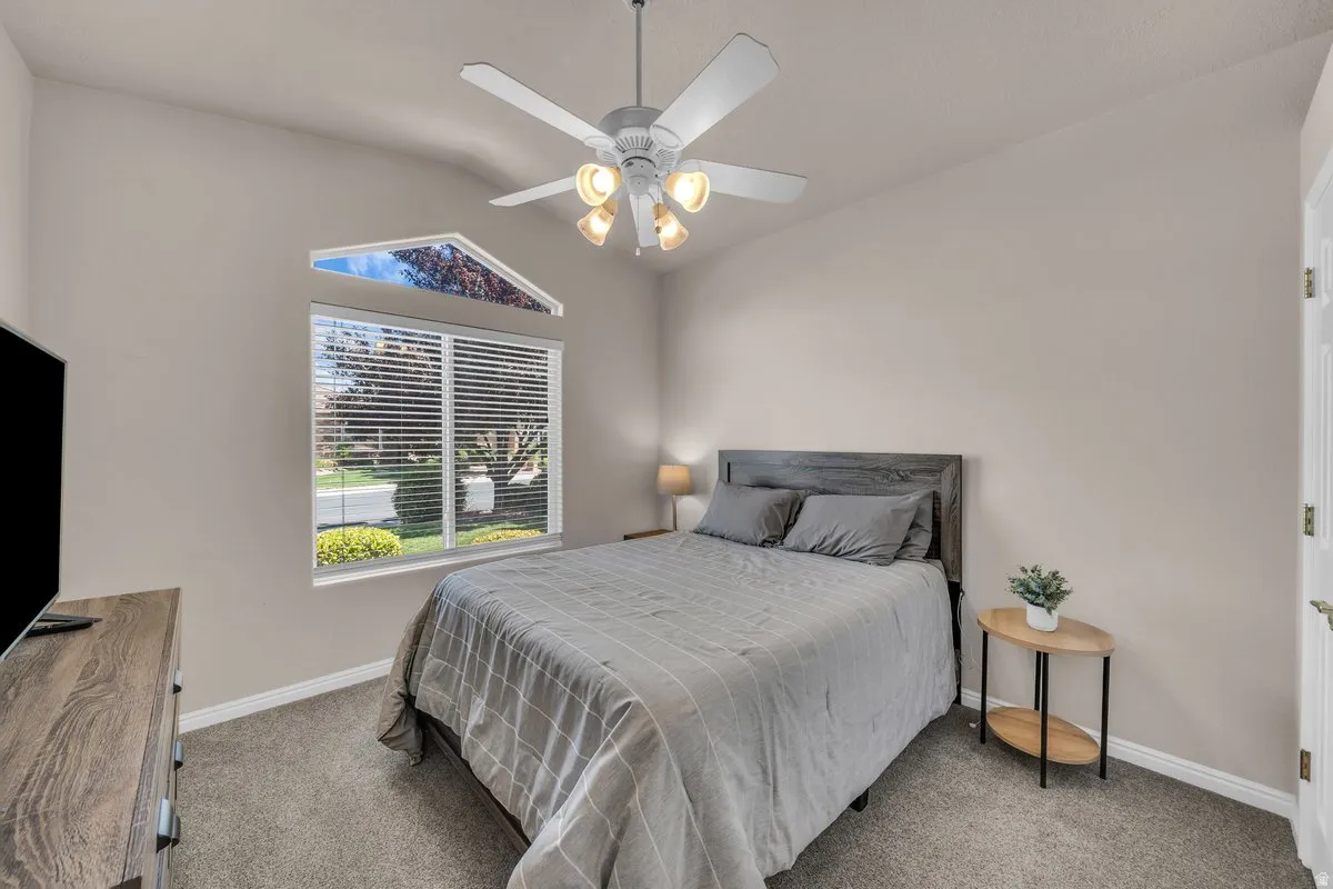 Bedroom with carpet floors, vaulted ceiling, and a ceiling fan