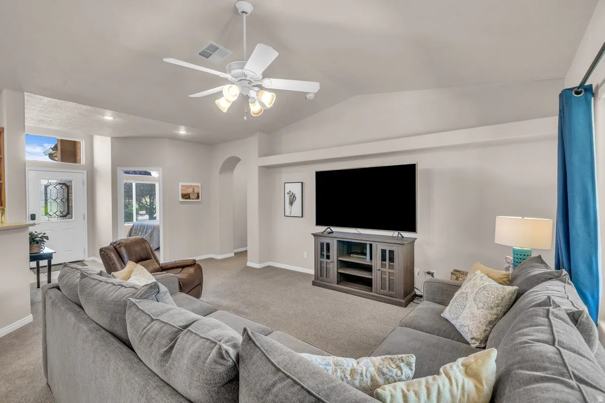 Living room with arched walkways, vaulted ceiling, carpet floors, a ceiling fan, and recessed lighting