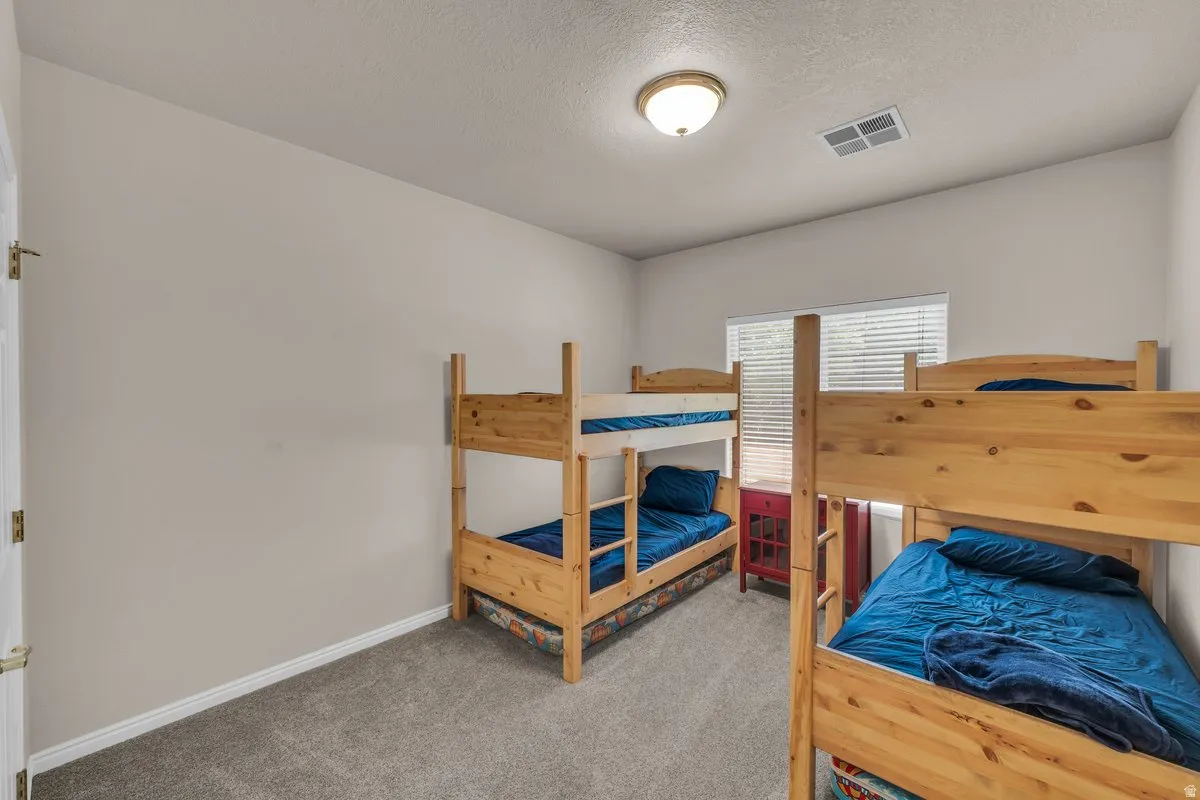 Carpeted bedroom featuring a textured ceiling and baseboards