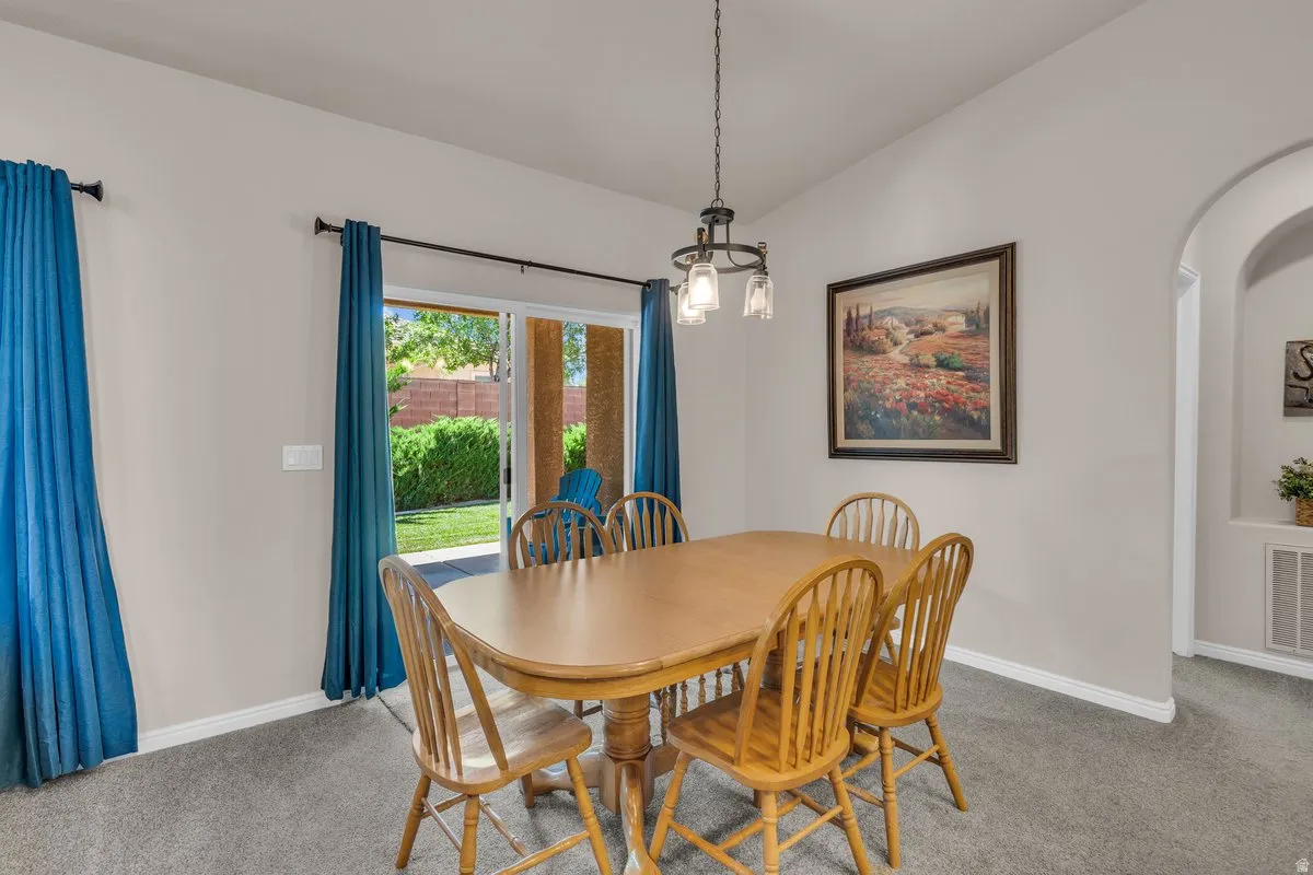 Dining space featuring arched walkways, carpet flooring, and lofted ceiling