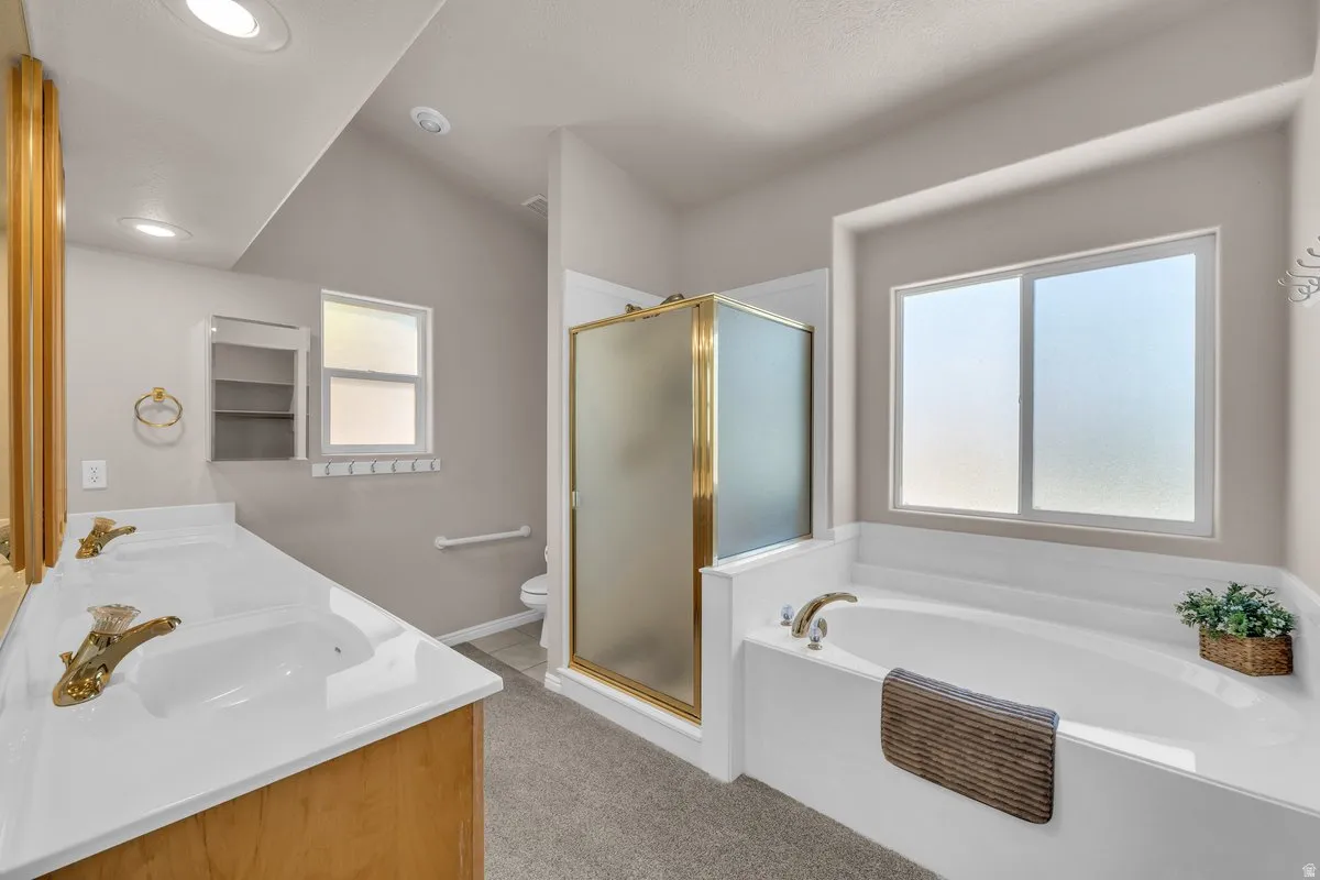 Full bathroom with double vanity, a bath, and a stall shower