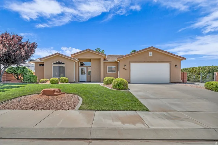 View of front of property with stucco siding, an attached garage, and driveway