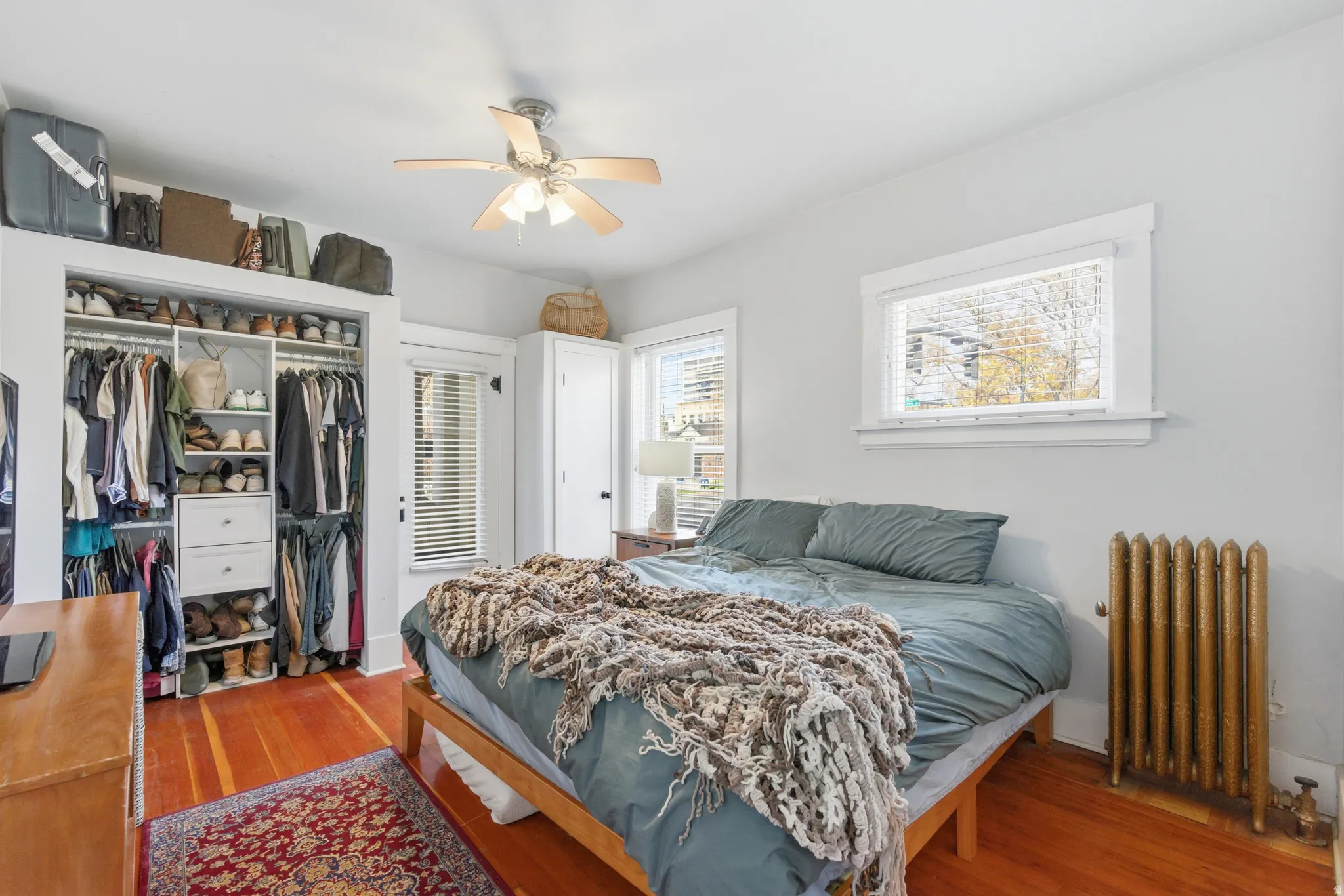 Bedroom featuring radiator, wood finished floors, a closet, and ceiling fan