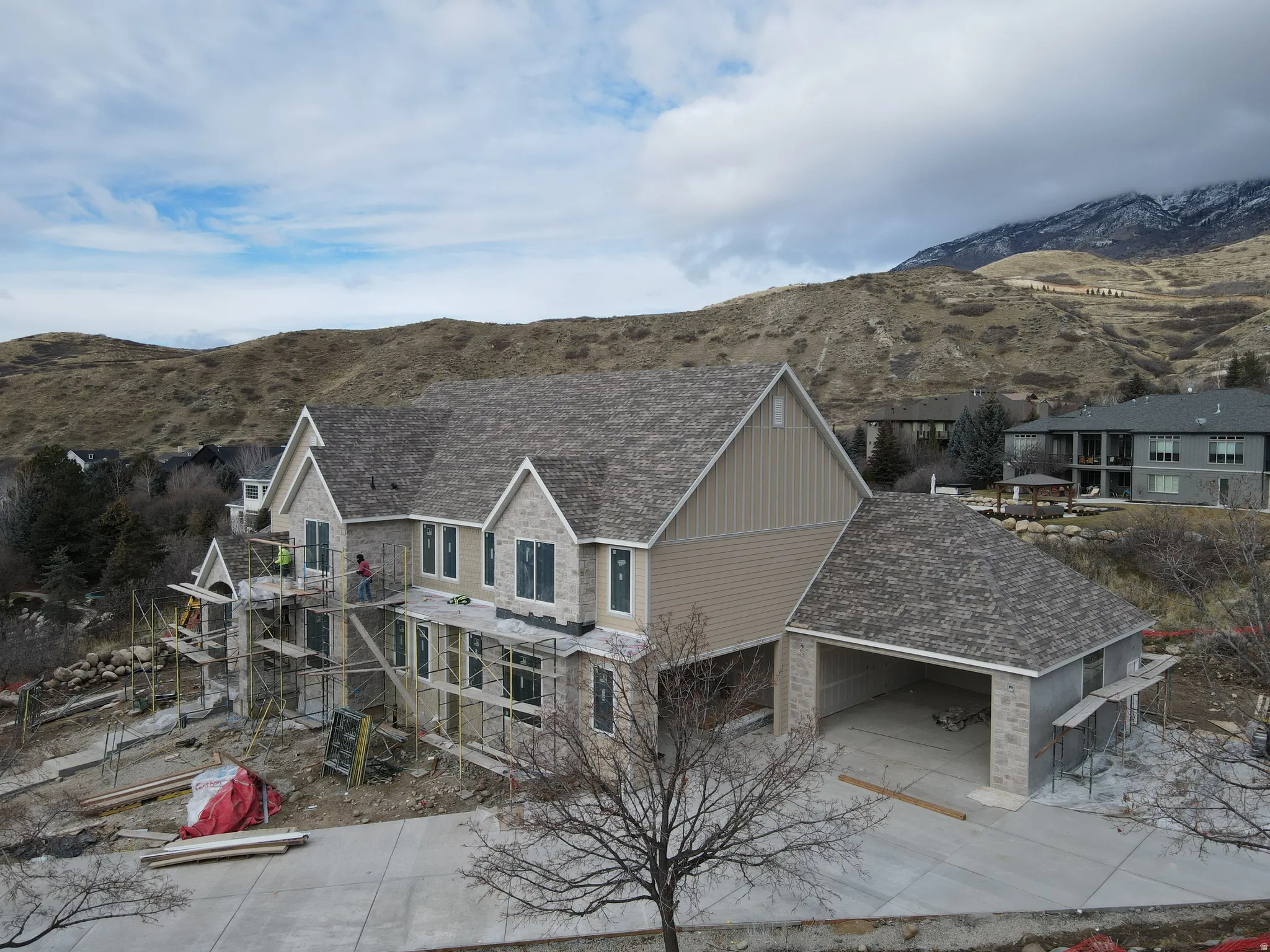 View of front facade with a patio, a mountain view, board and batten siding, and driveway