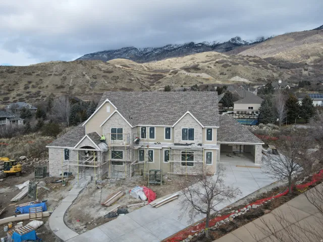 View of front facade with a mountain view, driveway, stone siding, and a patio