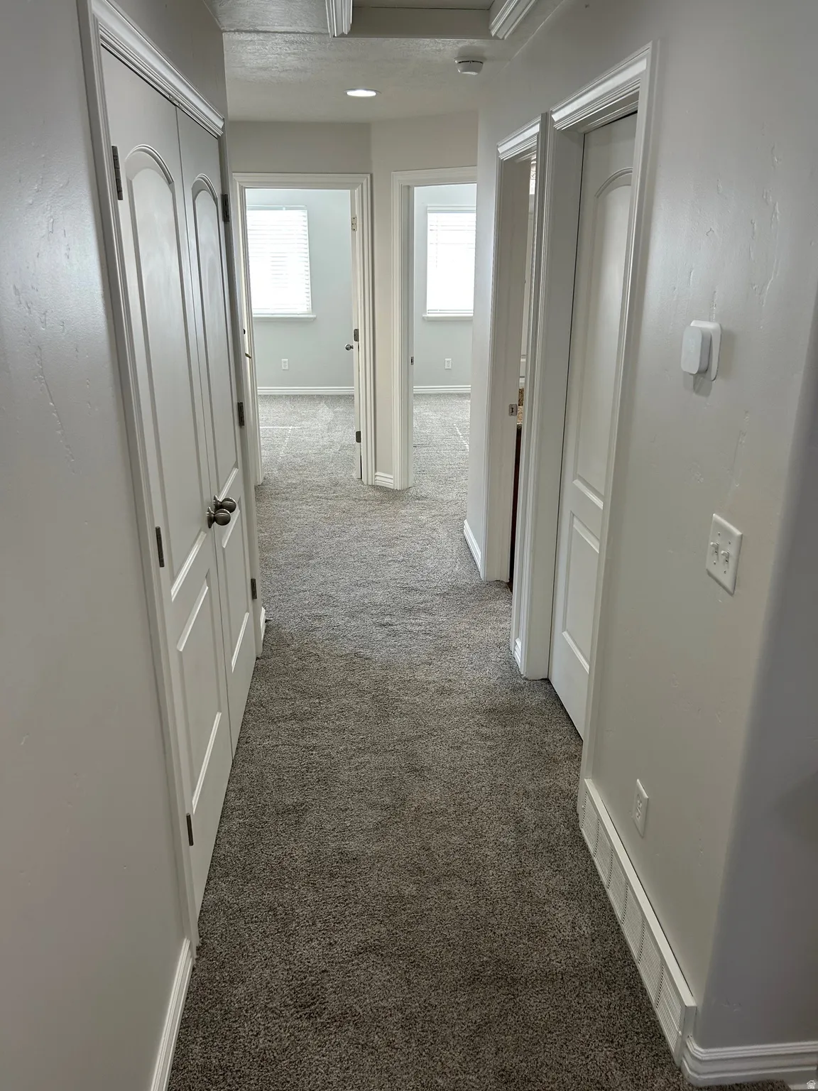 Hallway featuring dark carpet and baseboards