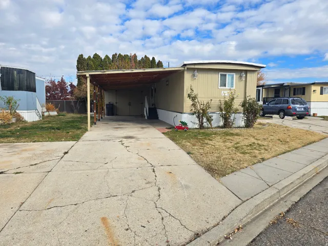 Manufactured / mobile home with concrete driveway and a carport