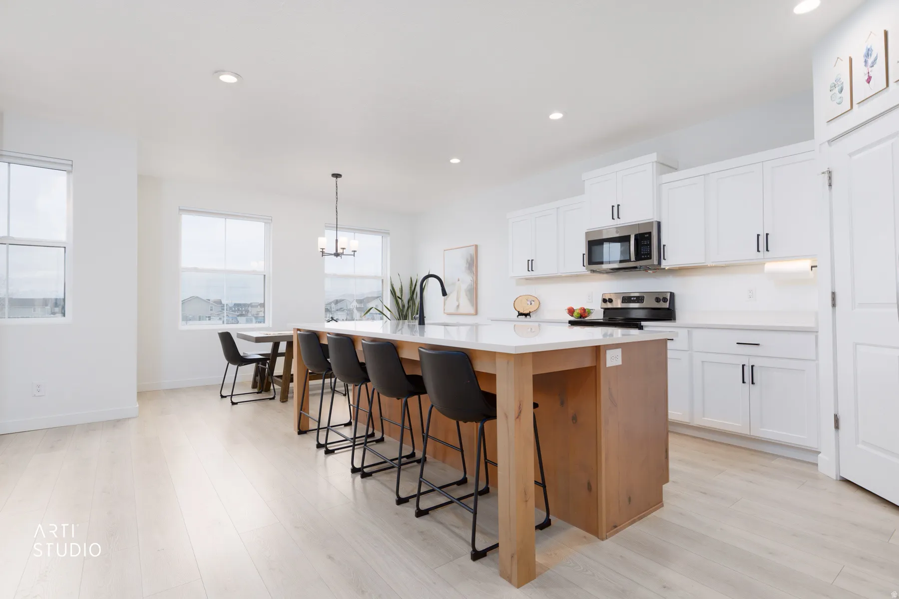 Kitchen featuring an island with sink, white cabinetry, hanging light fixtures, a breakfast bar area, and a chandelier