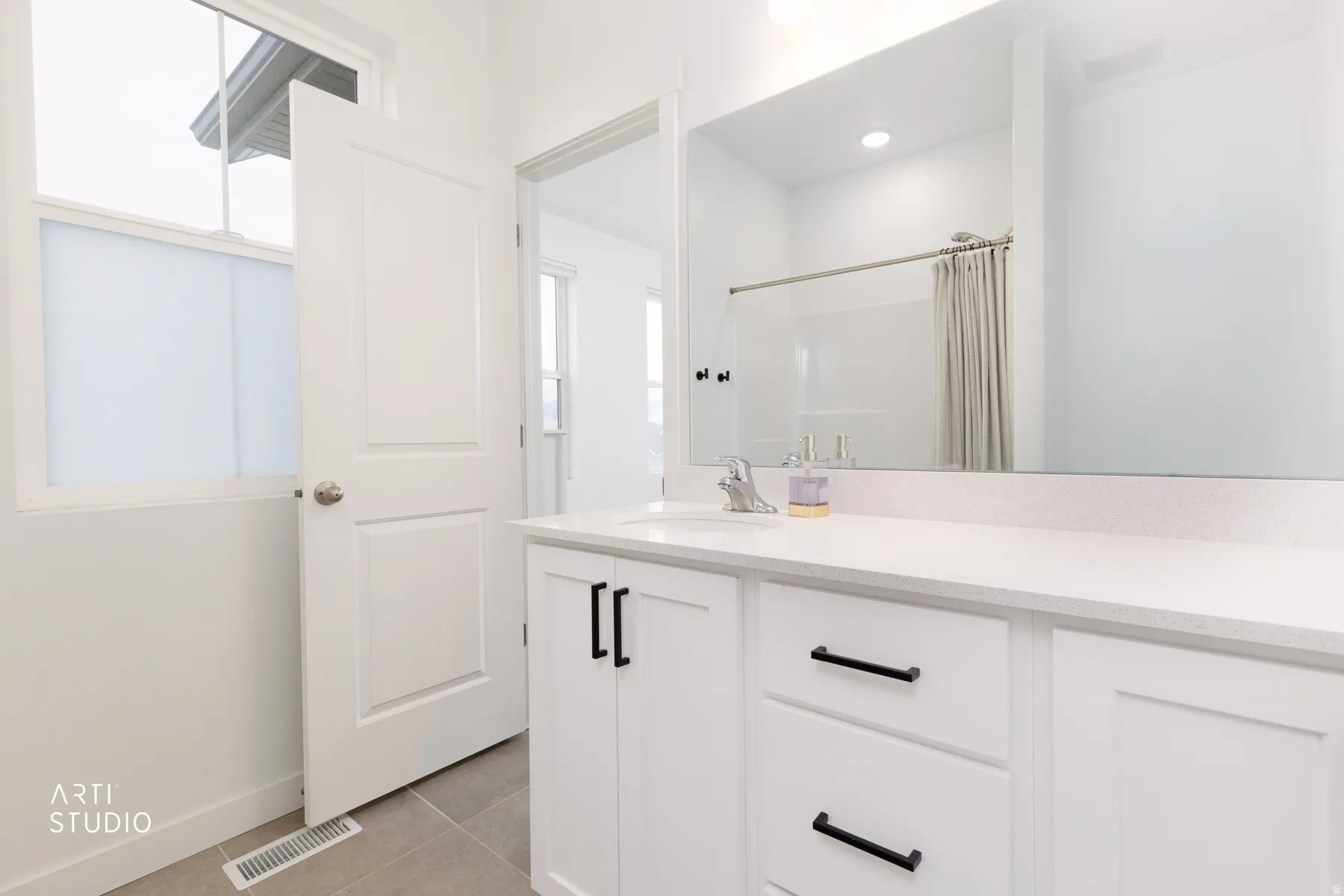 Bathroom with light tile patterned floors, vanity, curtained shower, and healthy amount of natural light