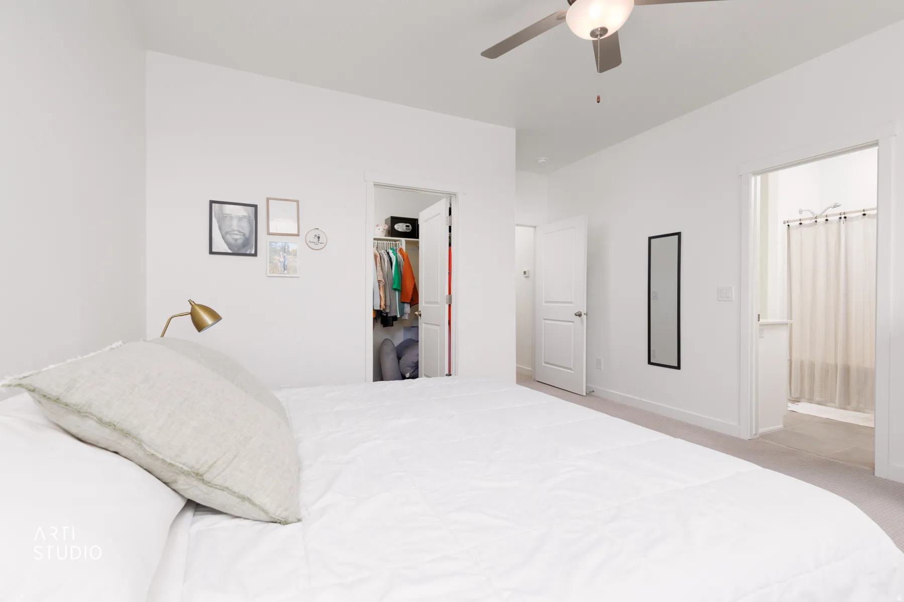 Bedroom with ensuite bath, a walk in closet, ceiling fan, and carpet
