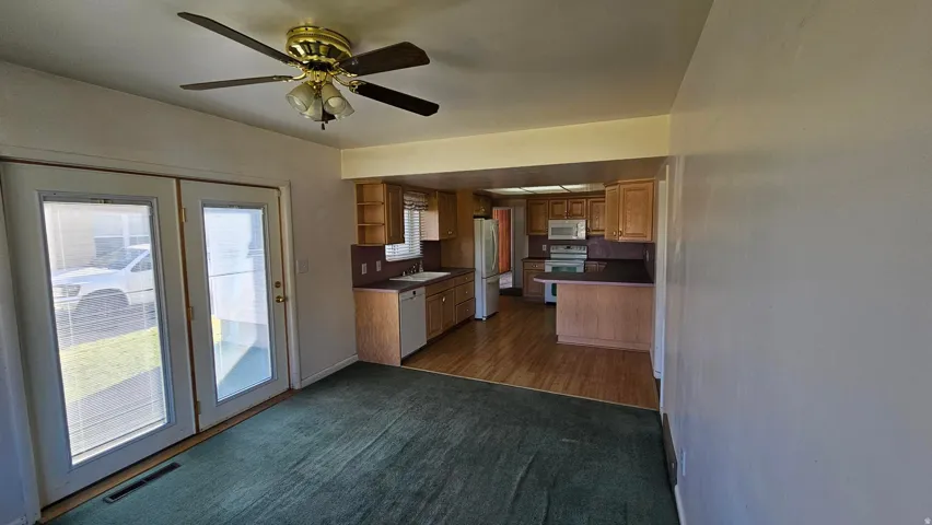 Kitchen with open shelves, range and range hood & microwave, freestanding refrigerator, brown cabinetry, and dark colored carpet
