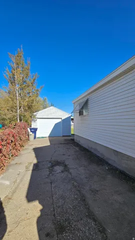 View of side of property with an outbuilding, a detached garage, and driveway